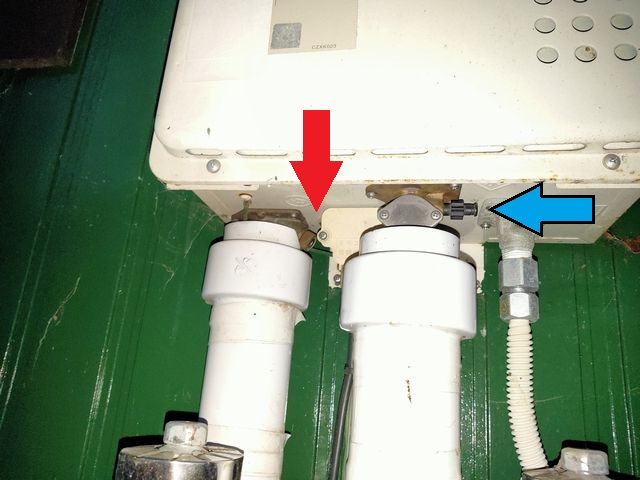 給湯器を下から見た画像：給湯管（赤の矢印）と給水管（青の矢印）の水抜き栓